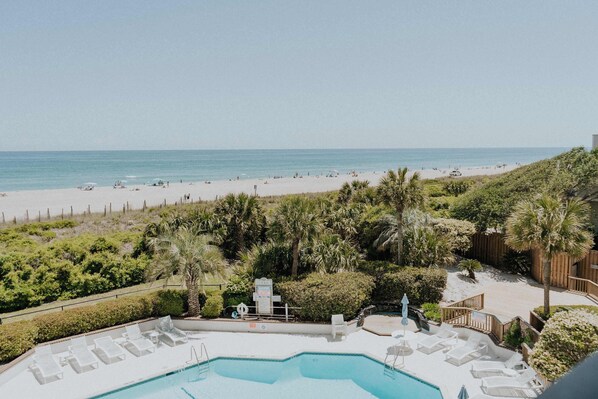 A pool area with lounge chairs, a sign, and a view of the beach. - Soulside 5G by Mira-Mar (Wrightsville Beach)