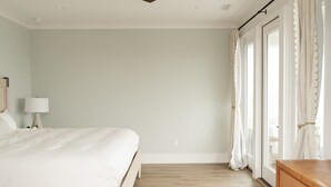 A bedroom with a bed, a nightstand, a lamp, a wooden dresser, and a ceiling fan. - 13 Raleigh- Ocean views, Private Pool and more (Wrightsville Beach)