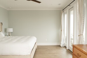 Ein Schlafzimmer mit Bett, Nachttisch, Lampe, Holzkommode und Deckenventilator.