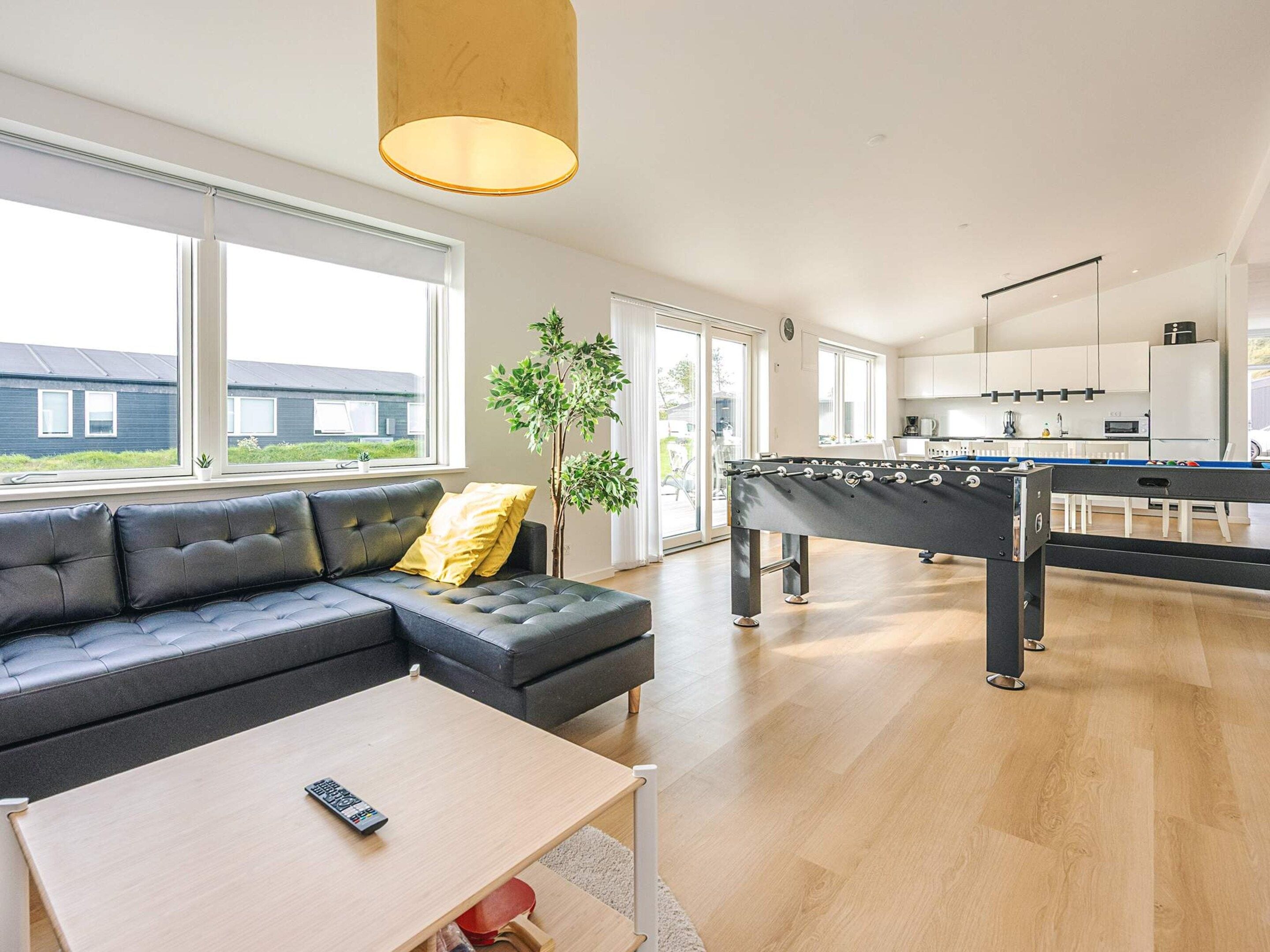 A modern living room with a sofa, coffee table, and a foosball table.