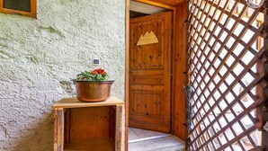 A rustic wooden door with a sign, a metal grate, and a wooden table with a copper pot. - L'Eau de Mai - PLANAY (PLANAY)