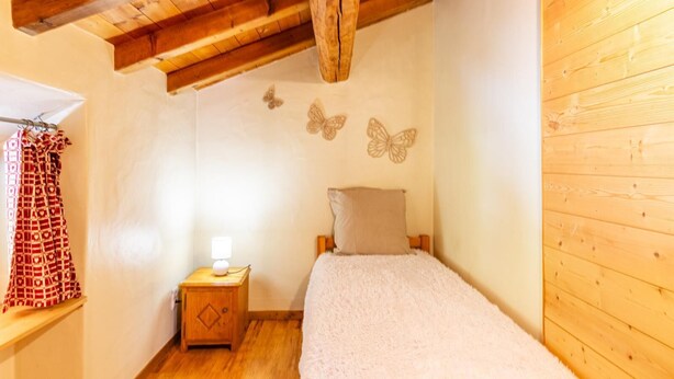 A bedroom with a wooden ceiling, a bed with a white blanket, a nightstand with a lamp, and butterfly wall decorations. - L'Eau de Mai - PLANAY (PLANAY)