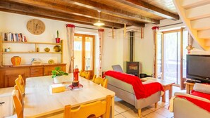 A cozy room with a wooden ceiling, a dining table, chairs, a sofa, a television, and a fireplace. - L'Eau de Mai - PLANAY (PLANAY)