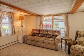Una habitación acogedora con sofá, una mesita, una lámpara y vistas al exterior.