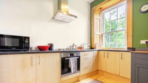 Eine Küche mit Holzausstattung, einer Mikrowelle, einem Backofen und einem Fenster mit Blick auf Grünflächen.
