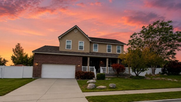 A two-story house with a garage, a front porch, and a well-maintained lawn.