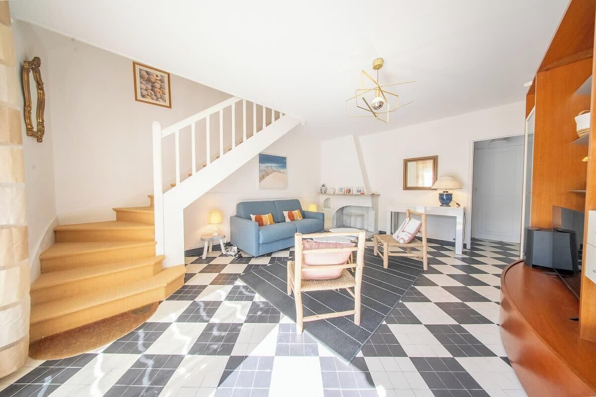 Un salon avec un sol à carreaux, un canapé bleu, un escalier et un meuble en bois.