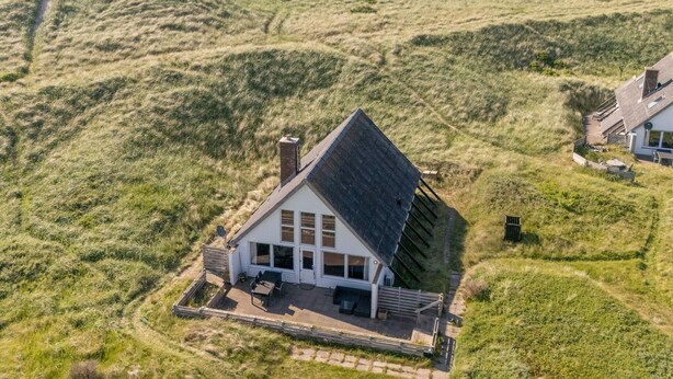 Une maison avec un toit en pente, de grandes fenêtres et un espace patio.