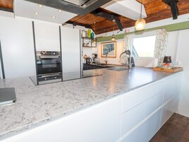 A modern kitchen with a central island, built-in oven, and a window with curtains.