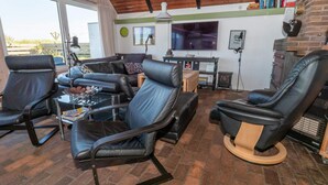 Un salon moderne avec des canapés en cuir, une table basse, une cheminée et un téléviseur.