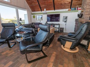 Ein modernes Wohnzimmer mit Ledersofas, einem Couchtisch, einem Kamin und einem Fernseher.