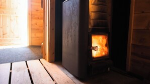 Ein Kaminofen mit sichtbarem Feuer, eine Bank und Holzwände.