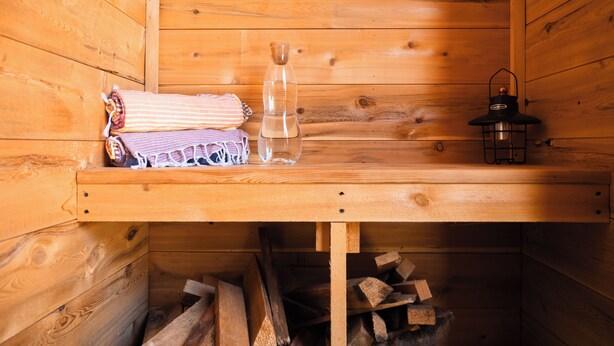 Ein Holzblockhaus-Interieur mit einer Bank, einer Laterne und einer Wasserflasche.