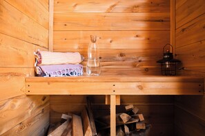 A wooden cabin interior with a bench, a lantern, and a bottle of water. - The Tipsy Butler Cottage & Sauna (Newcastle)