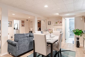 A modern living room with a dining area, a sofa, a table set for two, and a potted plant.