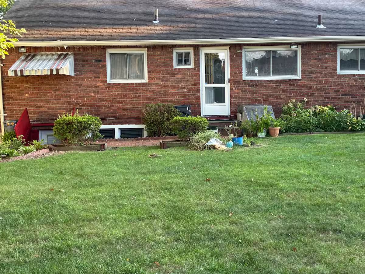 A single-story brick house with a front door, a small porch, and a well-maintained lawn.