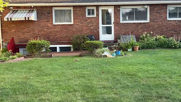 A single-story brick house with a front door, a small porch, and a well-maintained lawn.