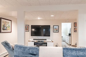 A living room with a flat-screen TV, a sofa, and a coffee table.