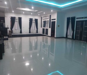 Una habitación amplia con piso pulido, iluminación empotrada en el techo y un gran ventanal con cortinas.