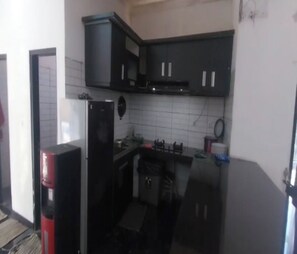 Una cocina compacta con armarios negros, un refrigerador y un microondas.
