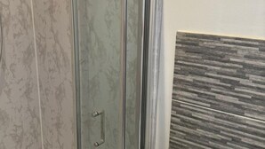 A bathroom with a glass shower enclosure and a tiled wall. - 4-bed House - Ensuite Rooms - Sleeps 8 - Parking (Manchester)