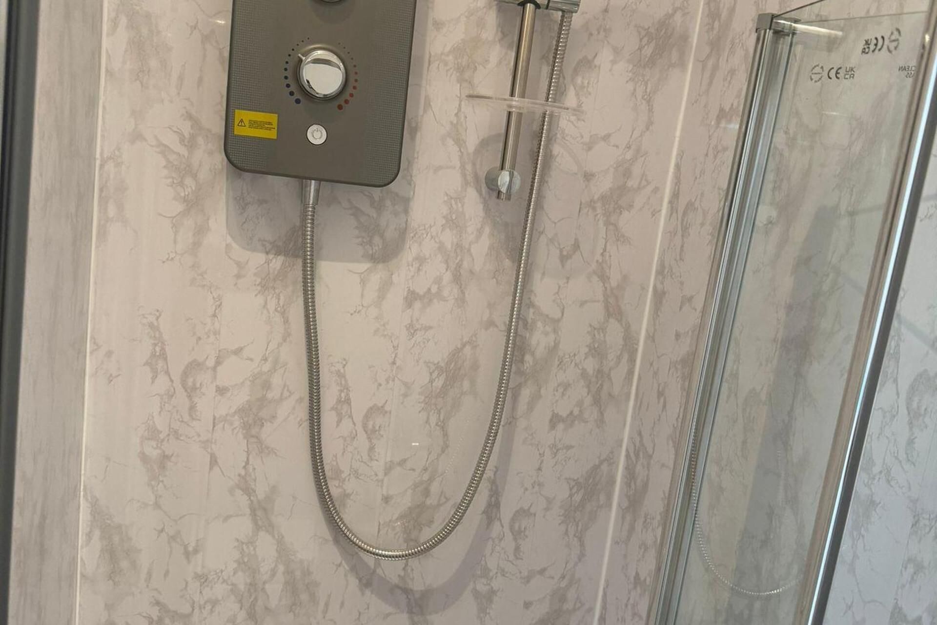 A shower with a control panel and a glass enclosure.