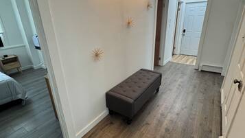 A hallway with a bench, a wall-mounted light, and a door.