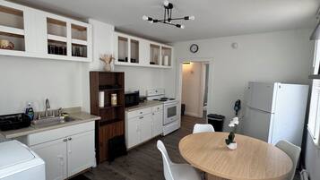 A modern kitchen with white cabinetry, a wooden dining table, and a built-in oven.