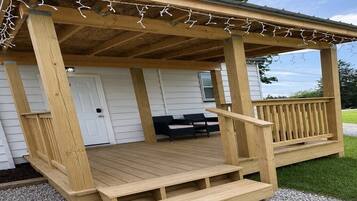 A wooden deck with a railing, steps, and string lights.