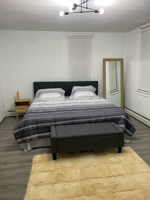 Une chambre à coucher comprenant un lit, une table de chevet, un miroir et un luminaire au plafond.