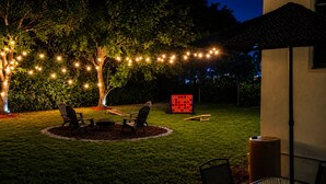 An outdoor seating area with chairs and a table, surrounded by a grassy lawn and trees. - Signature Stay 5 Minutes From Hard Rock Stadium (Miami Gardens)