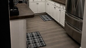 A modern kitchen with white cabinets, stainless steel appliances, and a black and white patterned rug. - Signature Stay 5 Minutes From Hard Rock Stadium (Miami Gardens)