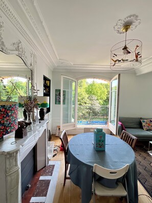 Ein Essbereich mit Tisch, Stühlen, einer Deckenleuchte und Blick ins Freie.
