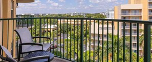 Un balcon avec deux chaises, une vue sur un quartier résidentiel et un immeuble en arrière-plan.
