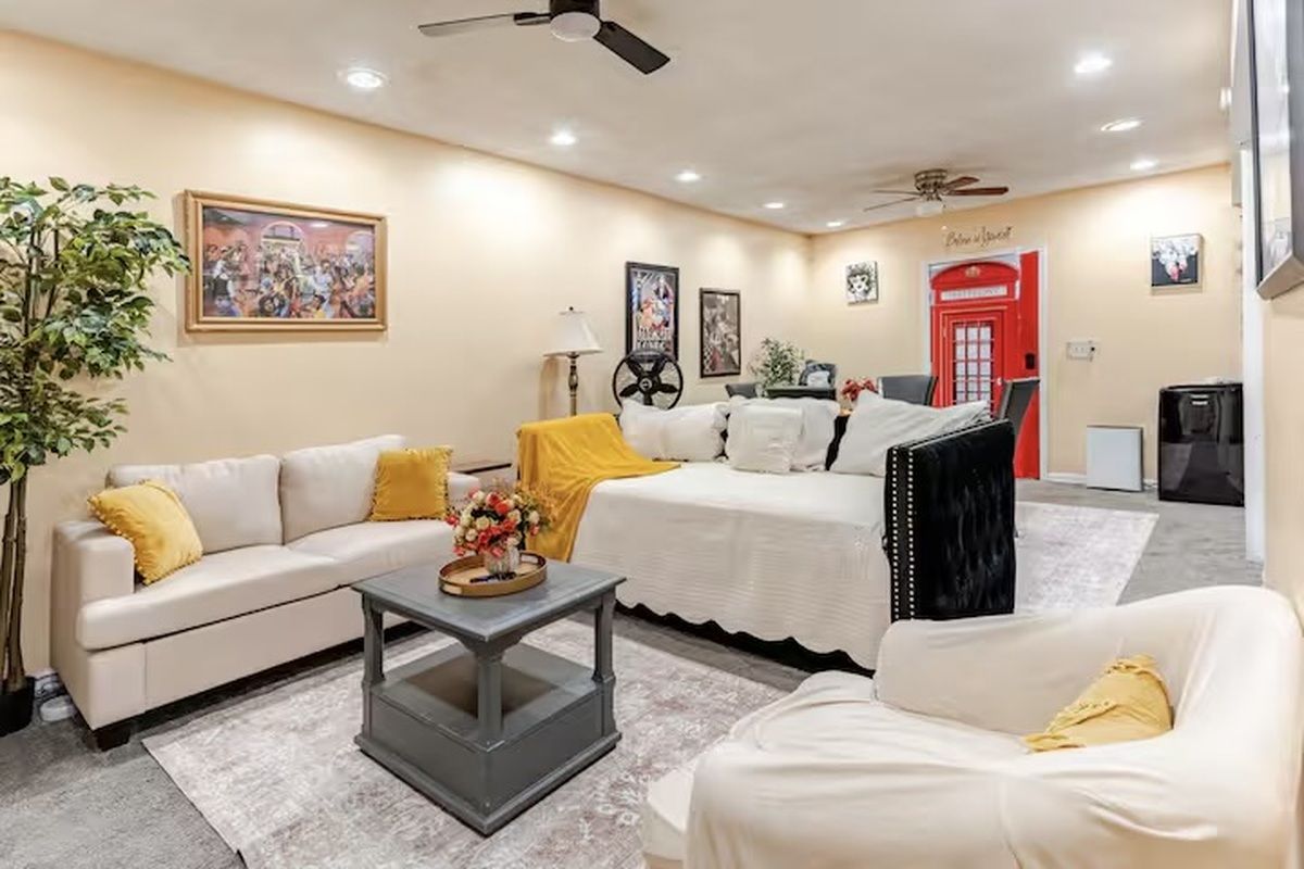 A hotel room with a sofa, a bed, a coffee table, and a red telephone booth.