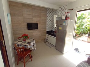 Eine kompakte Küche mit Esstisch, Stühlen, Fernseher und Kühlschrank.
