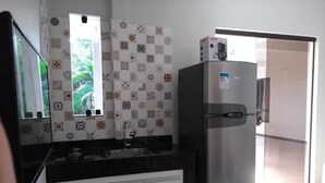 Una cocina con un refrigerador de acero inoxidable, un lavamanos y azulejos decorativos en la pared.