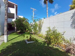 Ein Wohnhaus mit gepflegtem Rasen, weißer Außenwand und einer Palme.