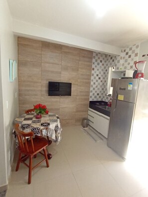 Eine kompakte Küche mit Essbereich, einem Wand-Fernseher und einem Kühlschrank.