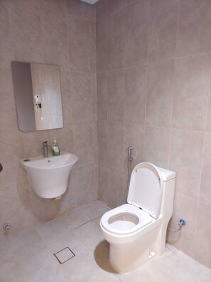 Et badeværelse med toilet, vask og spejl.