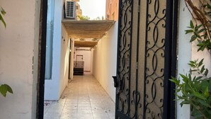 A narrow alleyway with a gated entrance, a tiled floor, and a building with a balcony. - OrbitNet-Al Khatim (Madina)