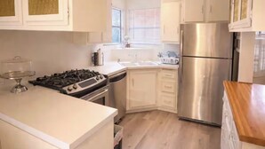 Eine moderne Küche mit weißen Schränken, Edelstahlgeräten und einer Holz Arbeitsplatte.