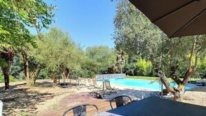 Un espacio al aire libre con piscina, terraza de madera y sillas de descanso.