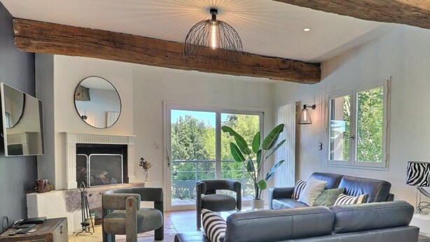 Una sala de estar moderna con chimenea, un sofá, zona de comedor y ventanas amplias.