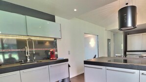 Una cocina moderna con armarios blancos, encimera negra y campana extractora de acero inoxidable.