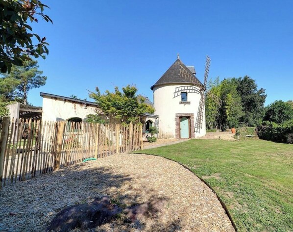 A round building with a conical roof, a wooden fence, and a grassy yard. - The Chicane Mill (ORGERES)