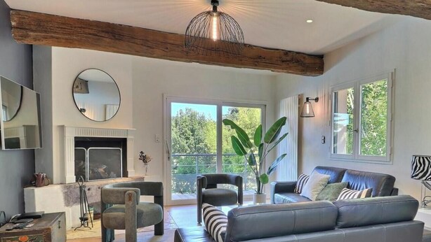 Una sala de estar moderna con chimenea, un sofá, una mesa de centro y un ventanal con vistas a zonas verdes.