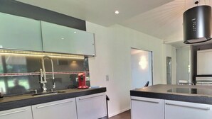 Una cocina moderna con electrodomésticos de acero inoxidable, armarios blancos y piso de madera.