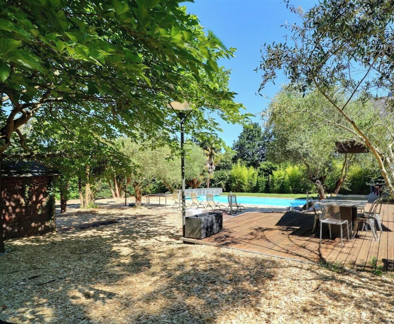 An outdoor area with a pool, wooden deck, and seating.