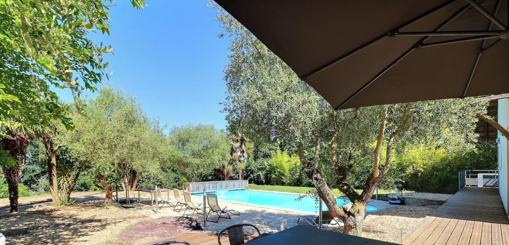 An outdoor area with a pool, wooden deck, and lounge chairs.